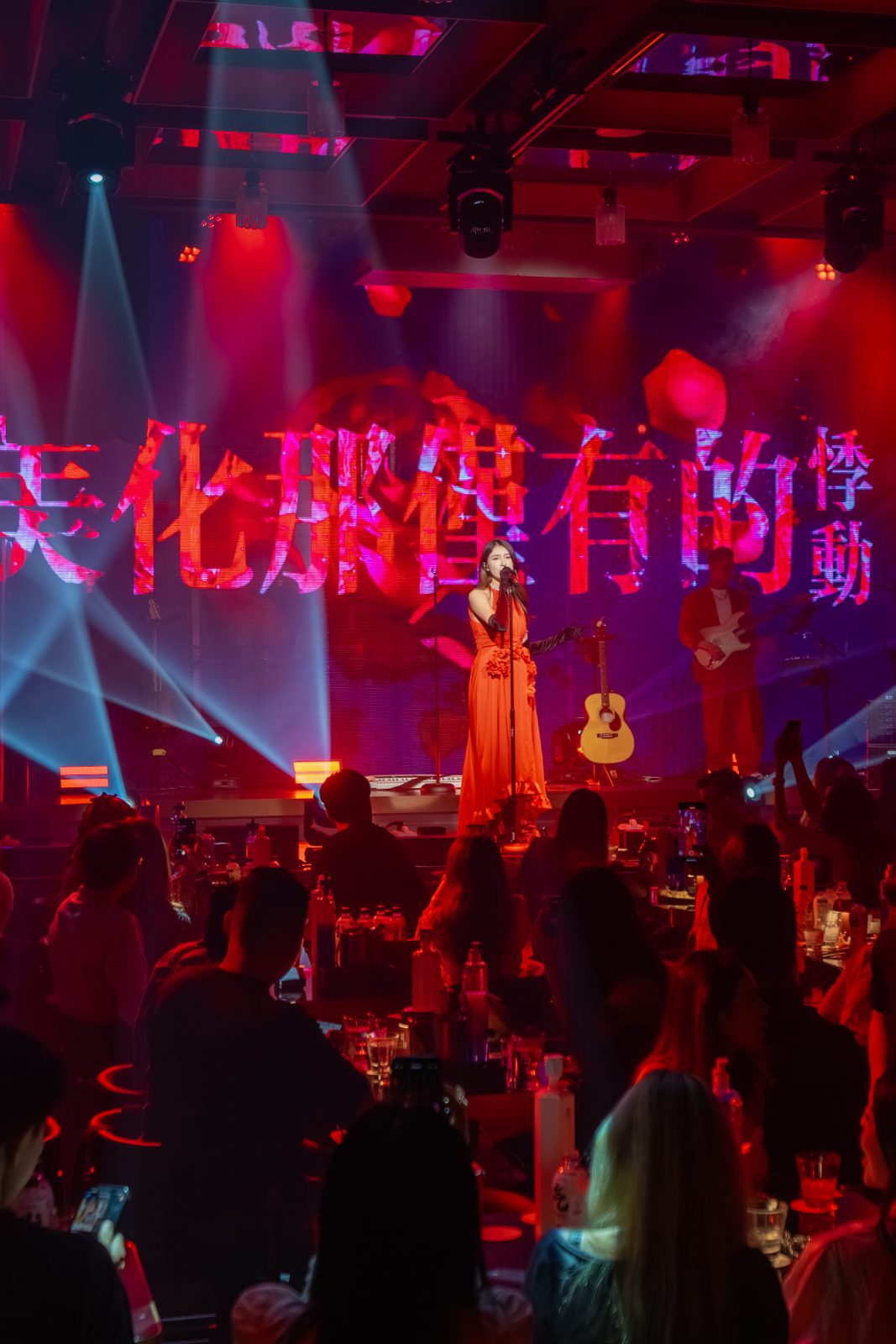 A performer under red stage lights and lyrics